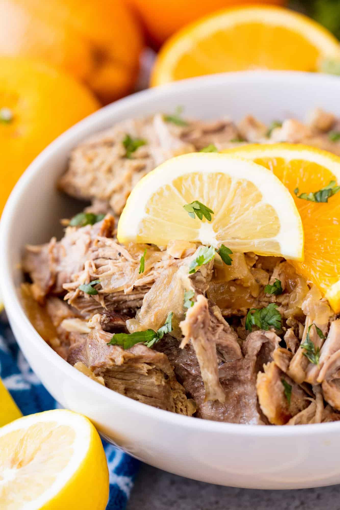 A bowl of Slow Cooker Cuban Mojo Pork garnished with chopped fresh cilantro and orange slices
