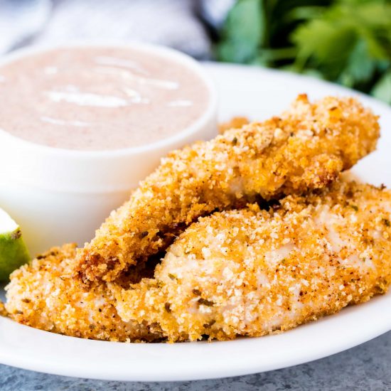 Chili-lime baked chicken tenders on a plate with Greek yogurt dipping sauce