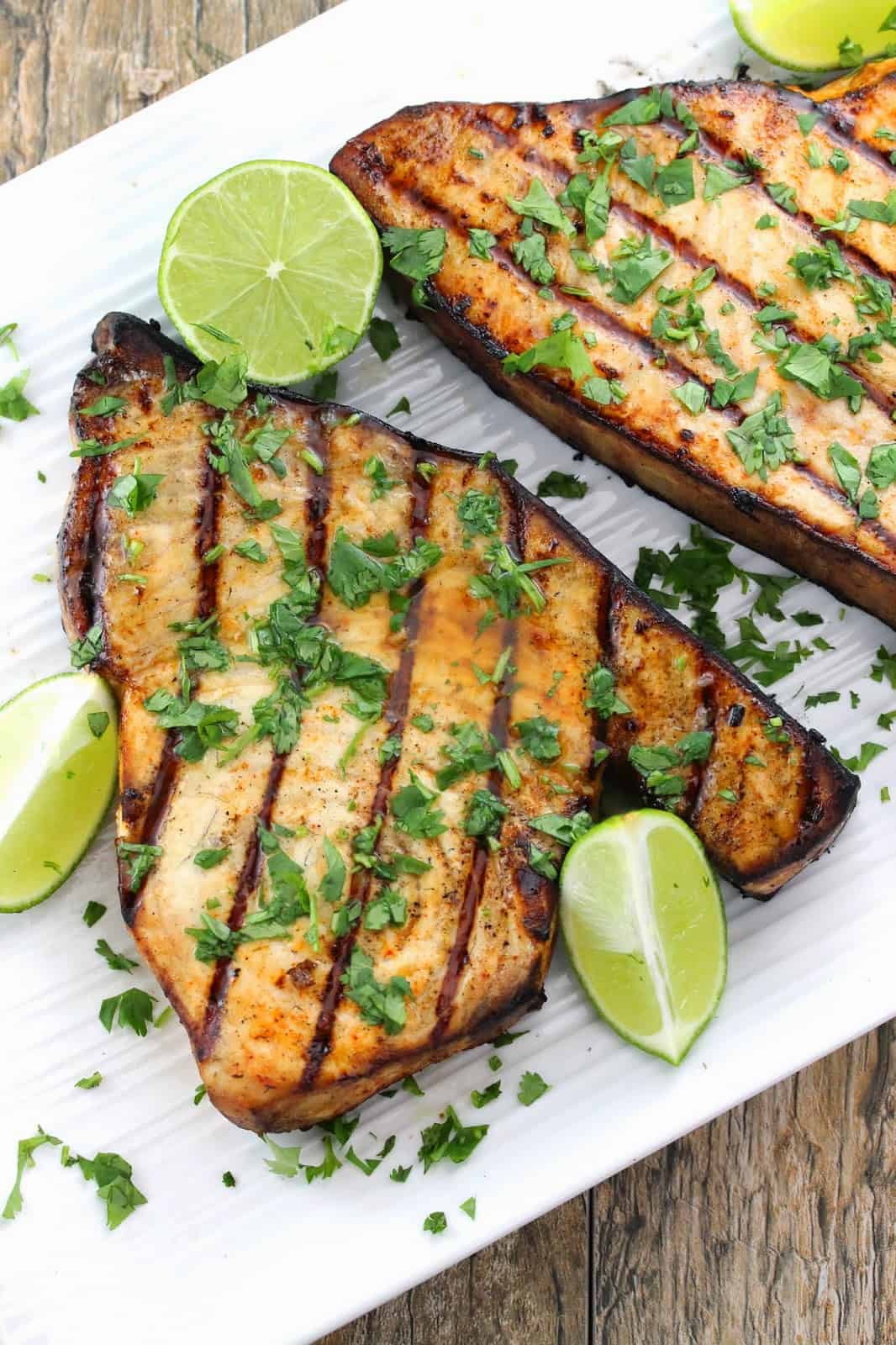 Grilled swordfish topped with cilantro and lime wedges