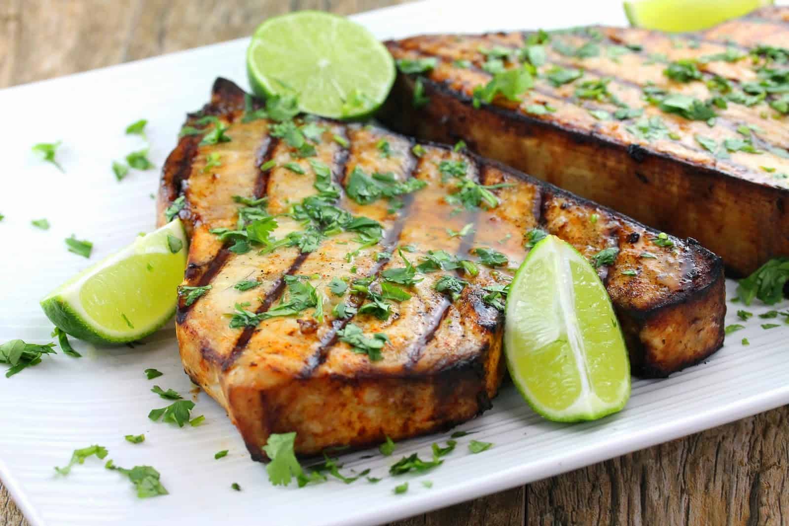Grilled swordfish topped with cilantro and lime wedges