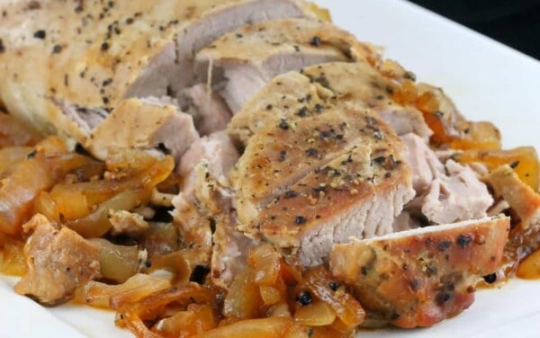 Slow Cooker Pork Tenderloin on a bed of onions on a white plate.