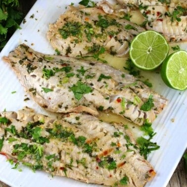 Thai Grilled Fish topped with parsley on a white plate.