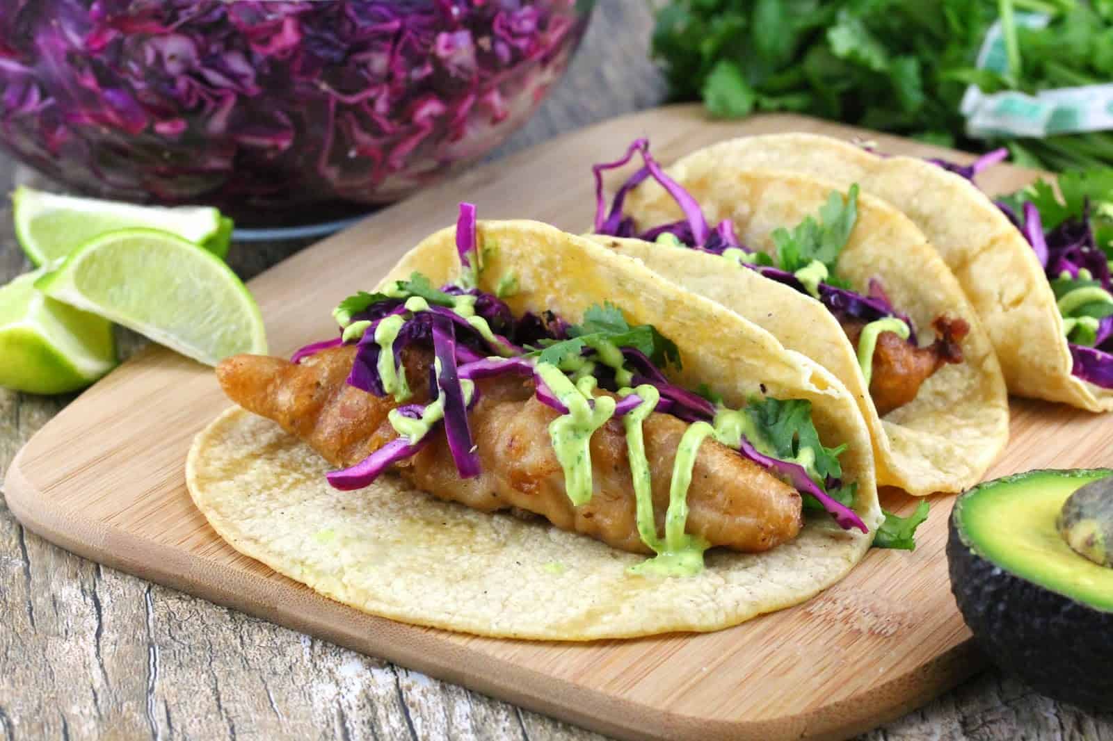 Dr. Pepper battered fish is wrapped in warm corn tortillas and topped with fresh cabbage slaw, avocado crema and garnished with cilantro and lime wedges.