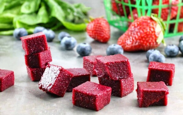 Cubes of Homemade Fruit and Vegetable Snacks stacked on a counter. These snacks are packed with fresh blueberry, strawberries and spinach