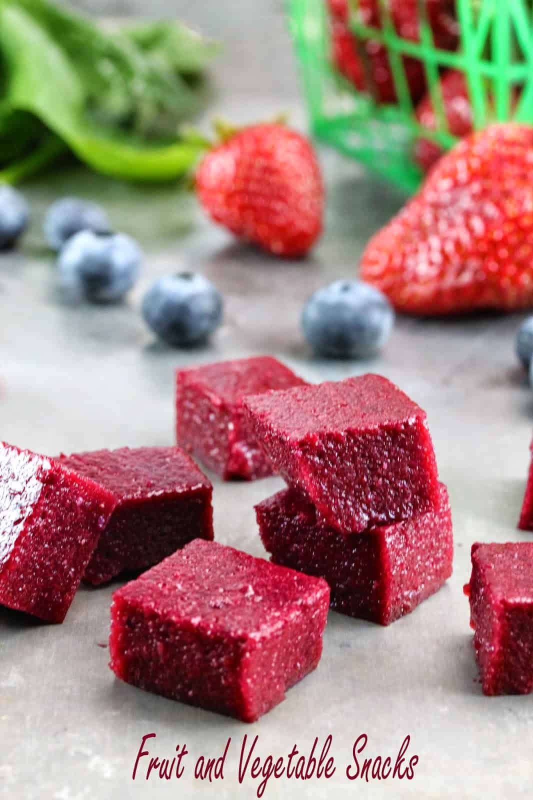 Cubes of Homemade Fruit and Vegetable Snacks stacked on a counter. These snacks are packed with fresh blueberry, strawberries and spinach