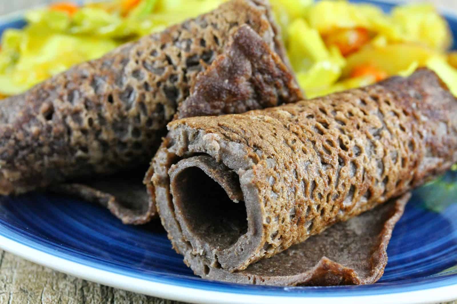 Close up of Ethiopian Injera flat bread on a blue plate by tikel gomen.