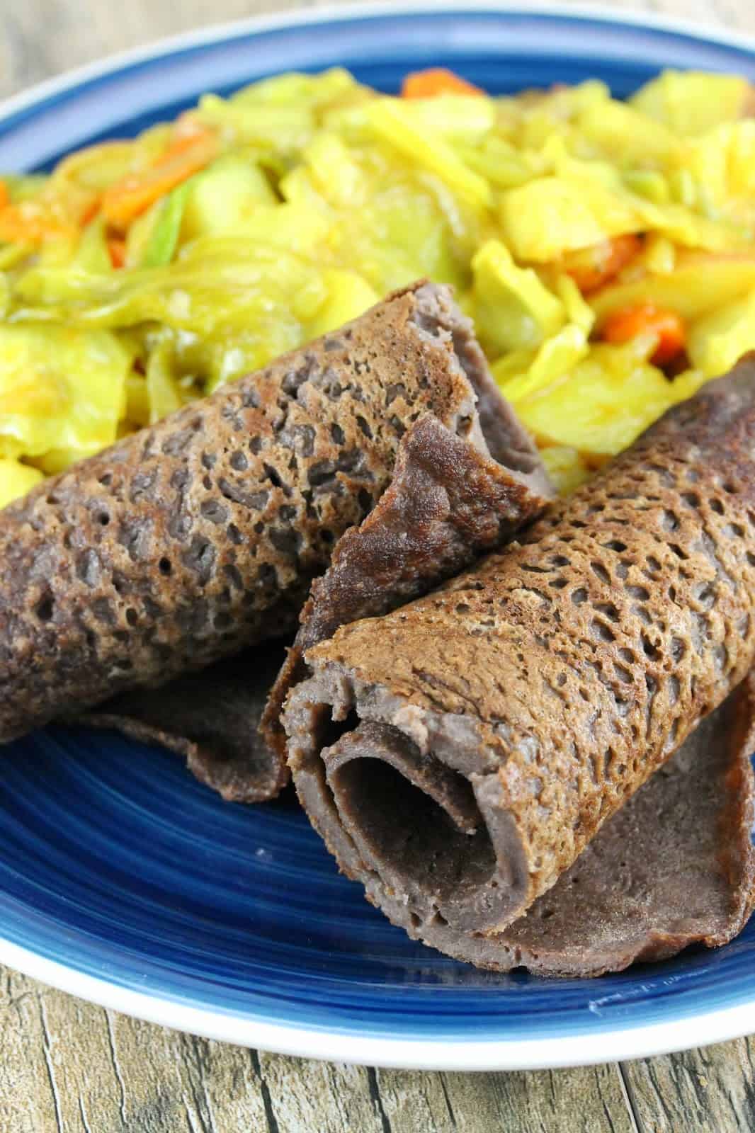 Ethiopian Injera Flat Bread is a staple in Ethiopian cuisine. A simple, unleavened bread made with teff flour. Here is rolled and served with Tikel Gomen