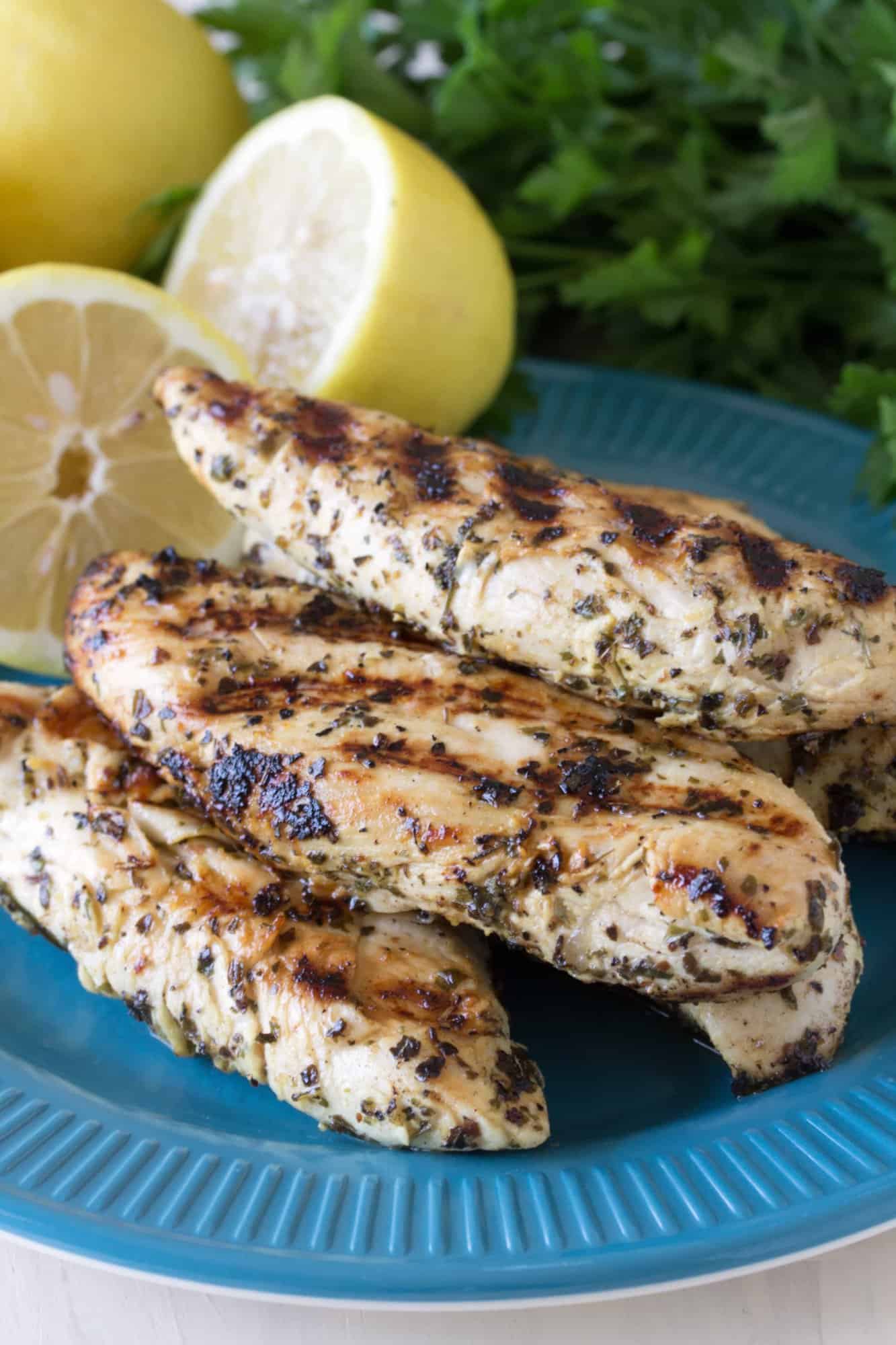 Grilled chicken tenders stacked on a blue plate.