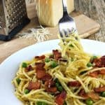 A fork swirls a bite of Quick Bacon and Pea Pasta (Eggless Spaghetti Carbonara) which is topped with crispy bacon and peas