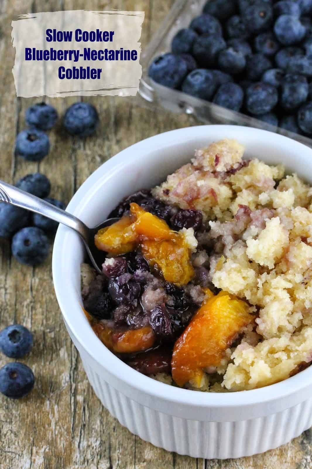 A spoonful of Slow Cooker Blueberry-Nectarine Cobbler is lifted from a bowl. This recipe is a great way to use fresh nectarines and blueberries