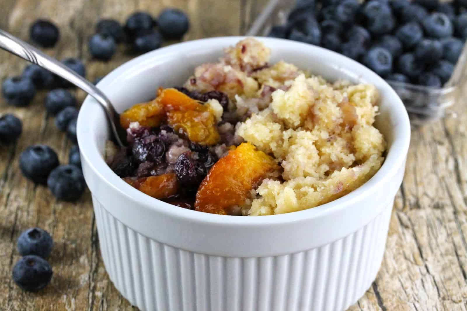 Slow Cooker Blueberry Nectarine Cobbler in a white bowl with a spoon in it.