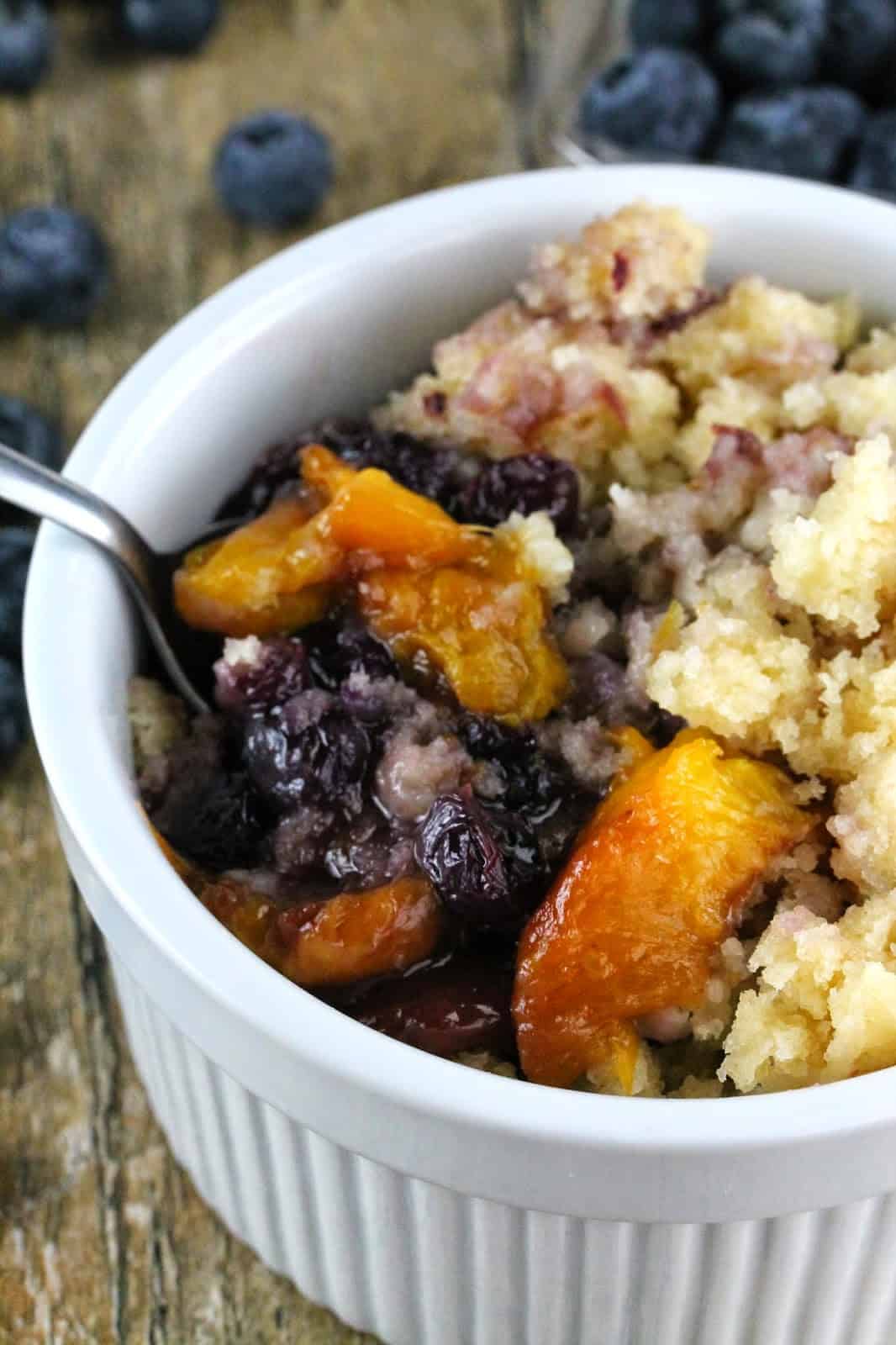 A spoonful of Slow Cooker Blueberry-Nectarine Cobbler is lifted from a bowl. This recipe is a great way to use fresh nectarines and blueberries