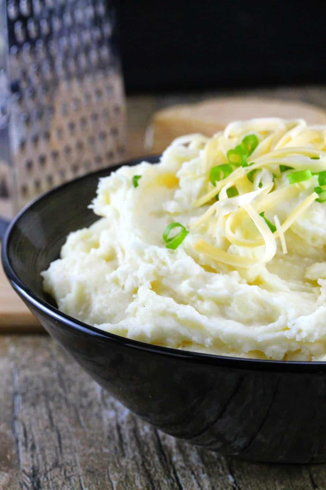 Close up of Smoked Gouda Mashed Potatoes served up with some freshly grated smoked gouda and chopped green onion