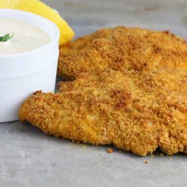 Curry chicken strips on a gray plate with a white bowl filled with curry dipping sauce