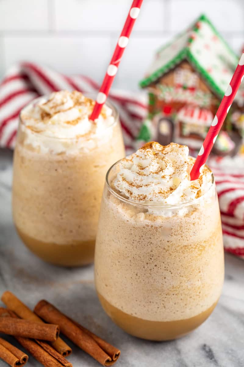 Gingersnap Frappe in two glasses with red polka dot straws, topped with whipped cream and dusted with cinnamon