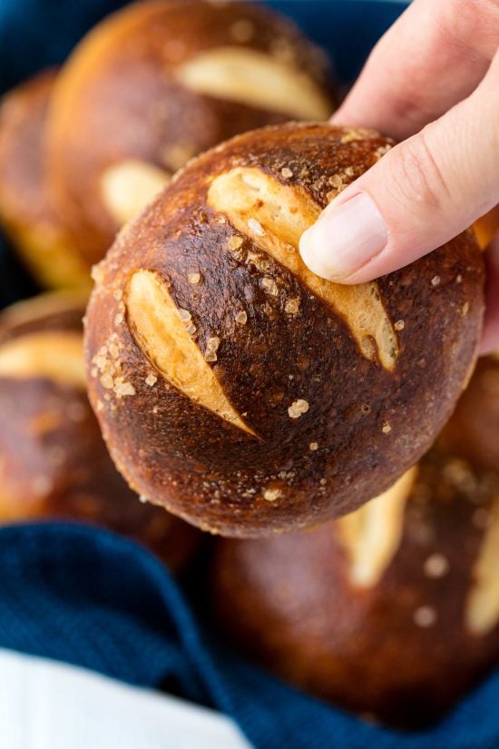 Hand holding a pretzel roll.