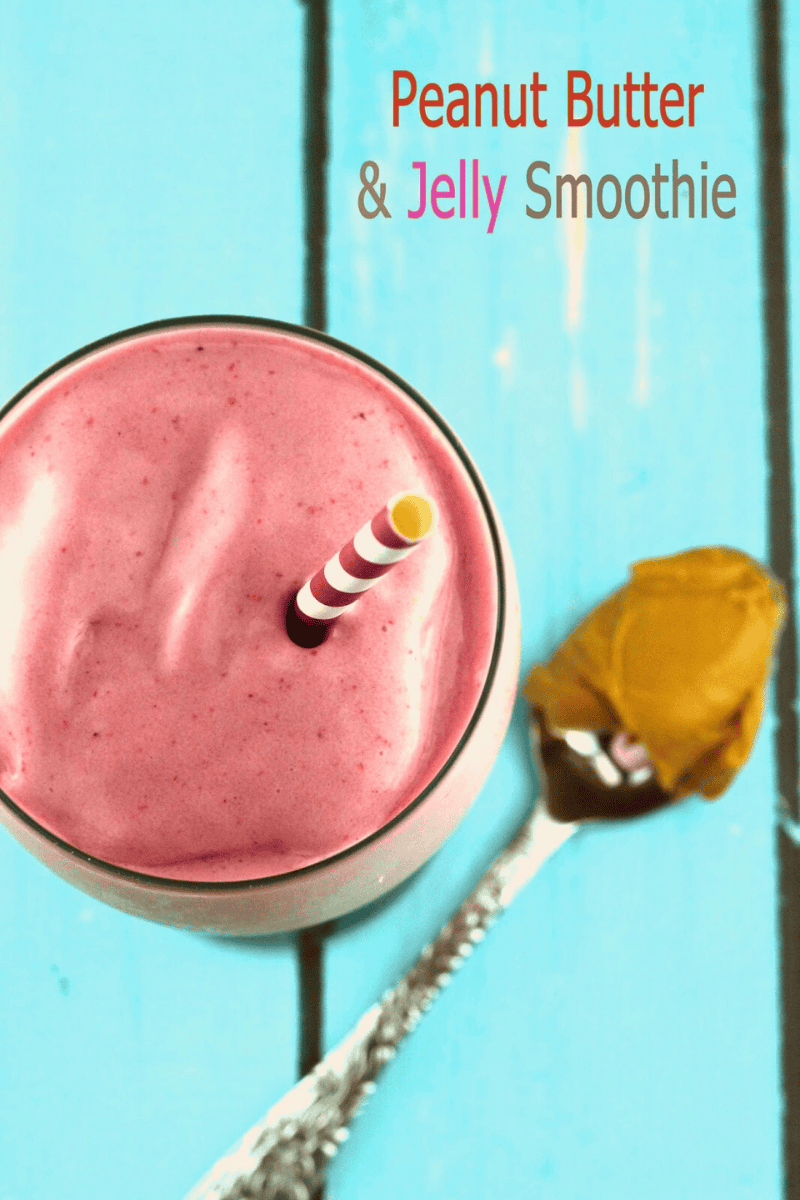 An overhead view of a pink peanut butter and jelly smoothie with a spoon of peanut butter laying next to it.