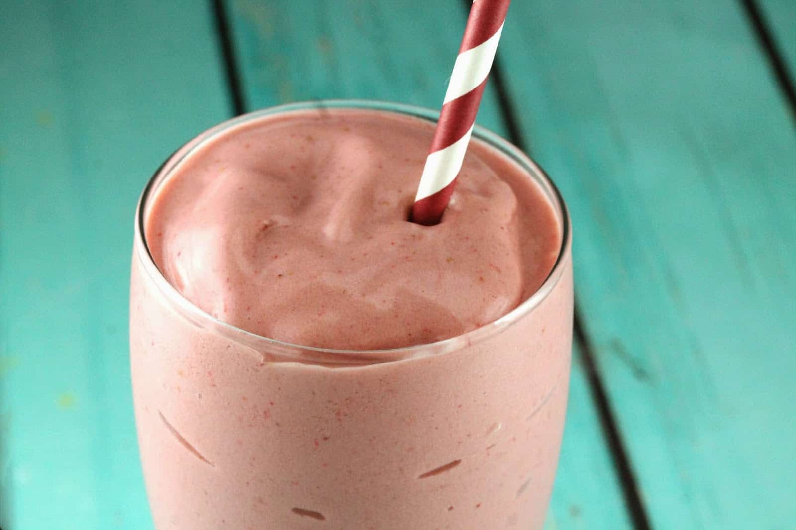 Peanut Butter and Jelly Smoothie in a glass with a straw coming out of it.