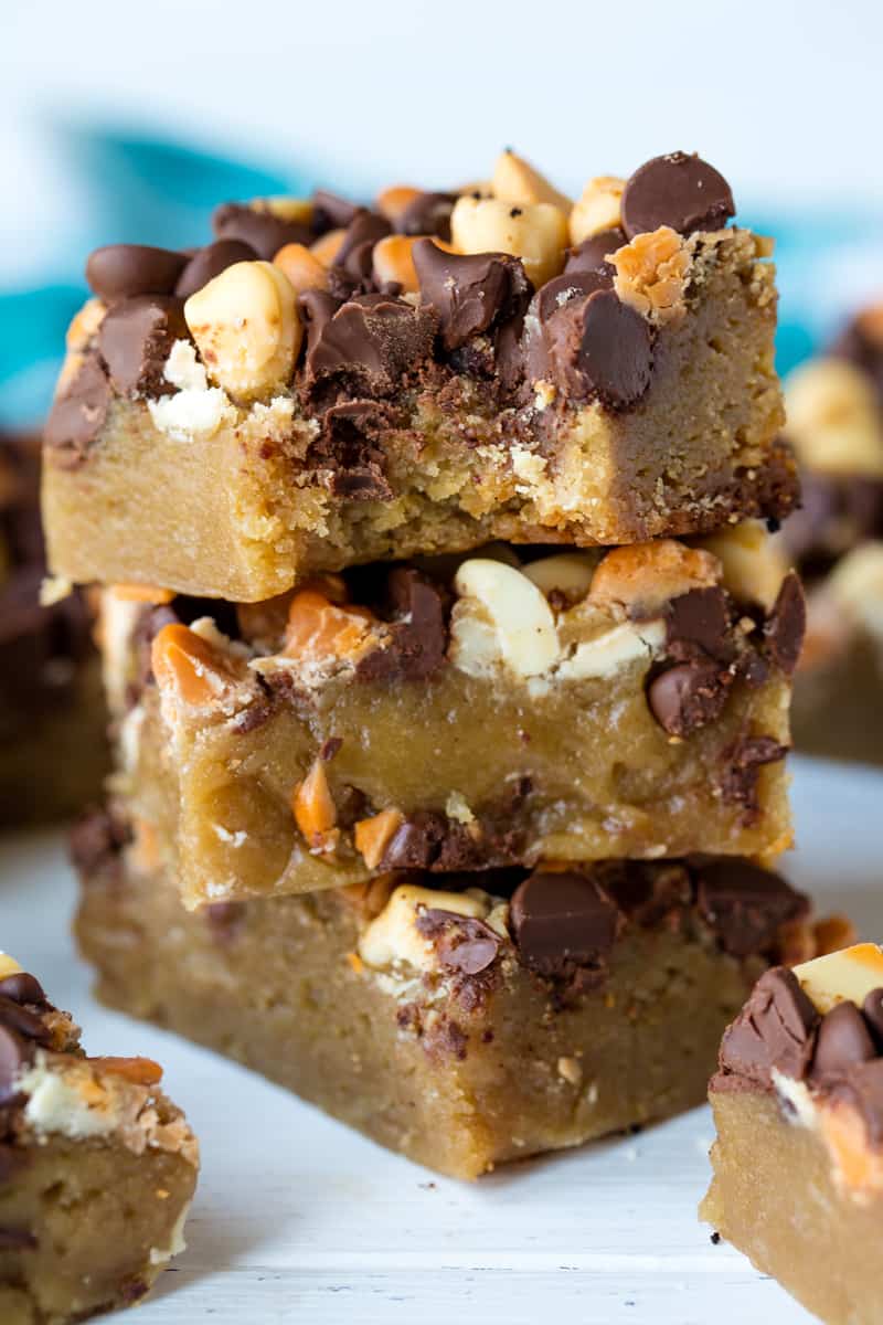 A stack of Slow Cooker Cookie Bars loaded with white chocolate and chocolate chips. A bite is taken out of the top cookie. Mmmm, delicious!
