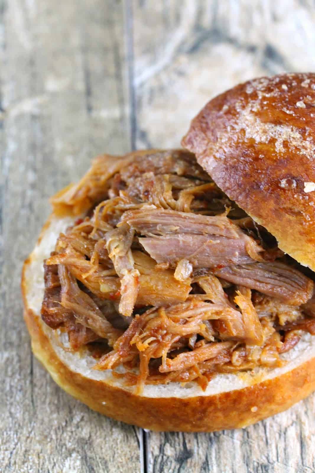 Slow cooker honey chipotle pulled pork sandwhich with the top bun half off.
