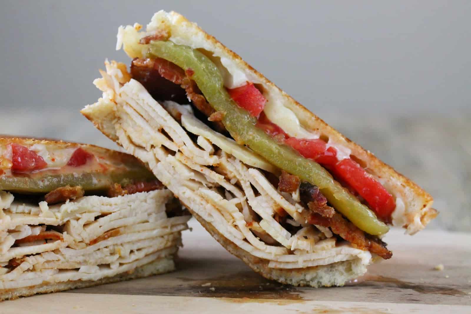 Baja Turkey Club cut in half and stacked on a countertop.