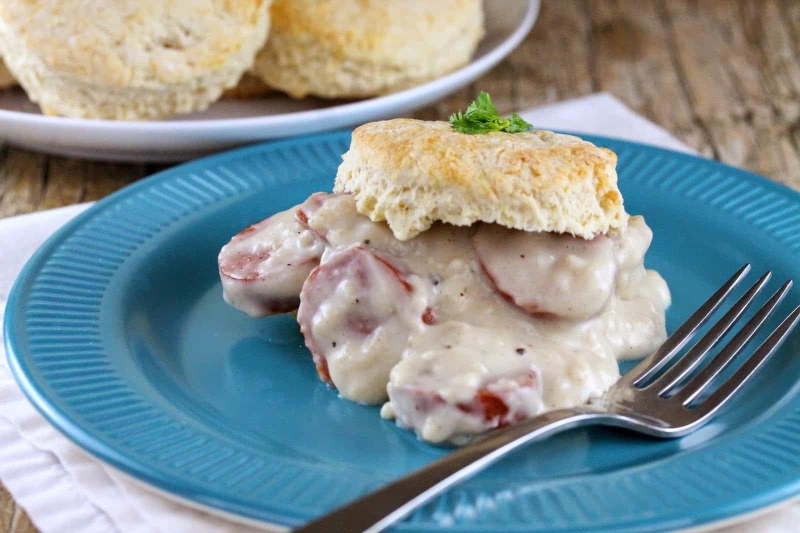 Gravy with slices of sausage is topped with a homemade biscuit and garnished with parsley