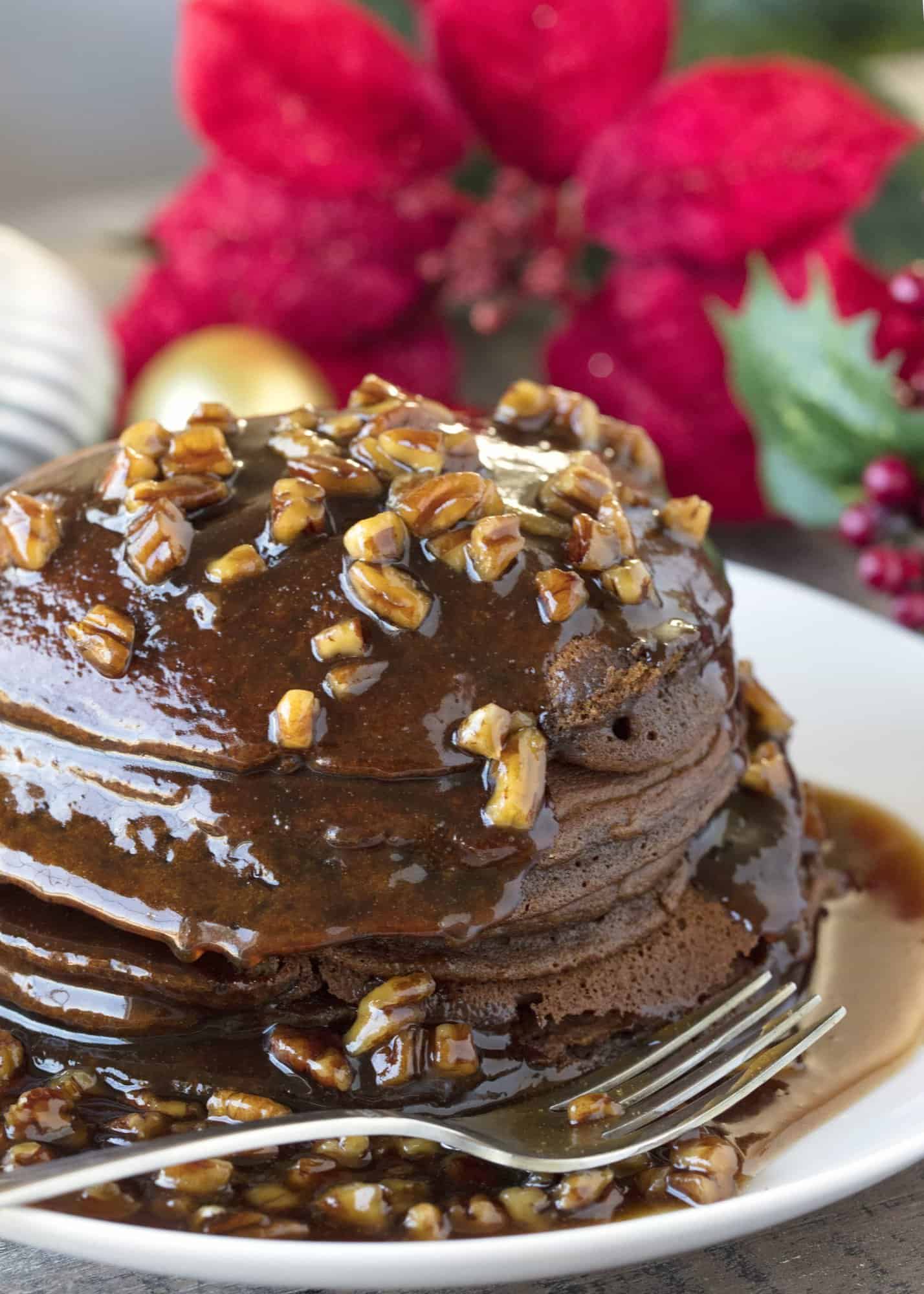 A stack of Gingerbread Pancakes on a plate, smothered with Butter Pecan Syrup and chopped pecans