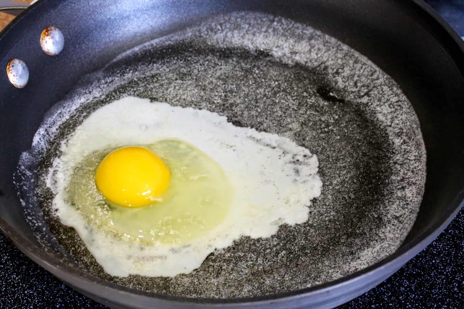 An egg being fried in butter in a skillet.