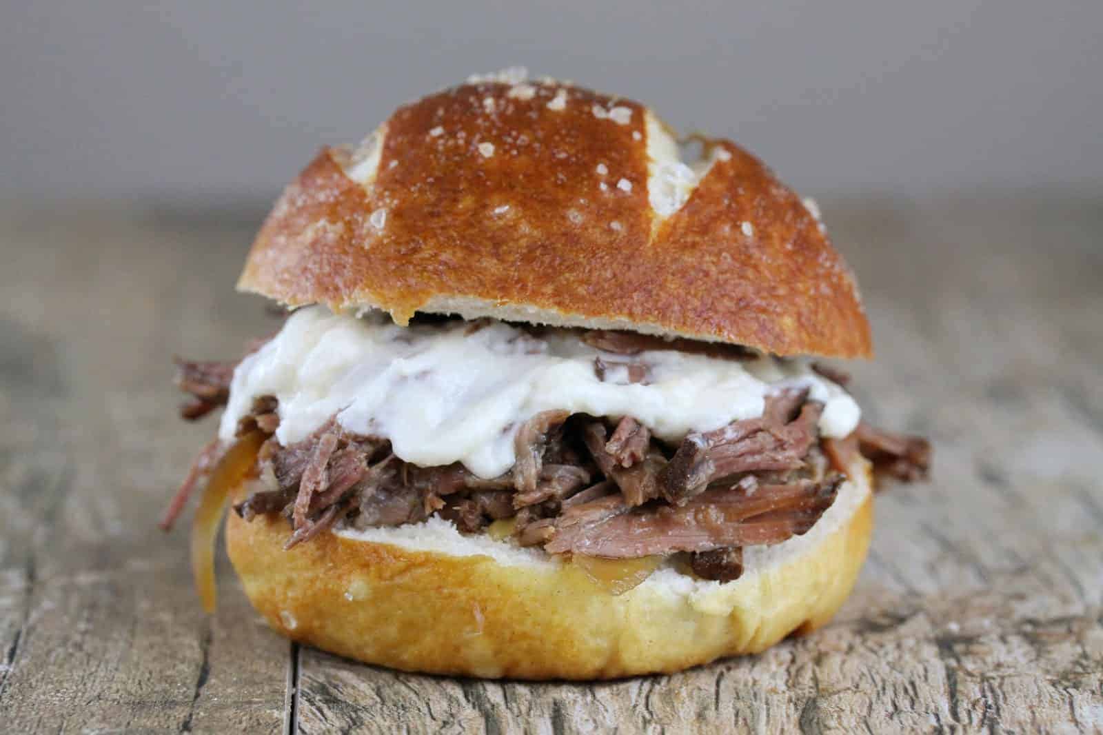 Slow Cooker Beef and horseradish sandwich with cheese on a woodentable.