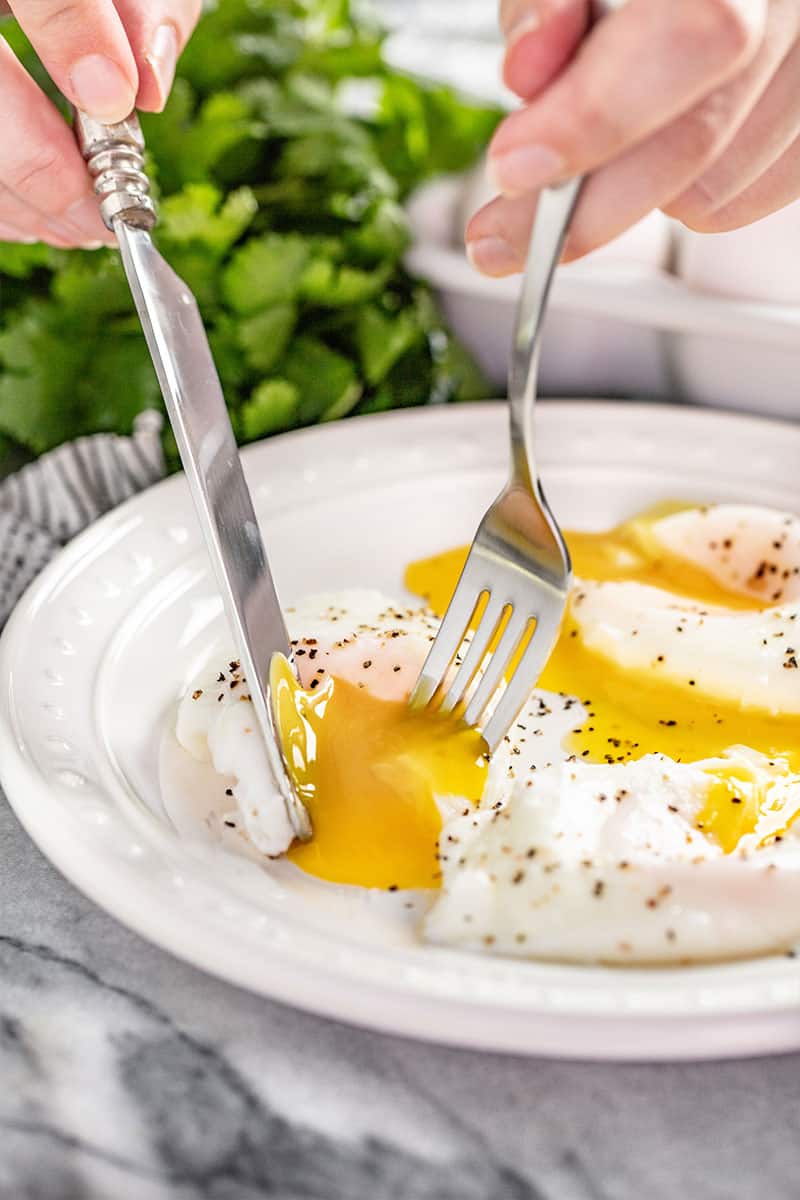 Poached Eggs cut into with a fork and knife, yolks running out