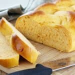 Braided Sweet Potato Bread on a cutting board with 2 slices taken out of it.