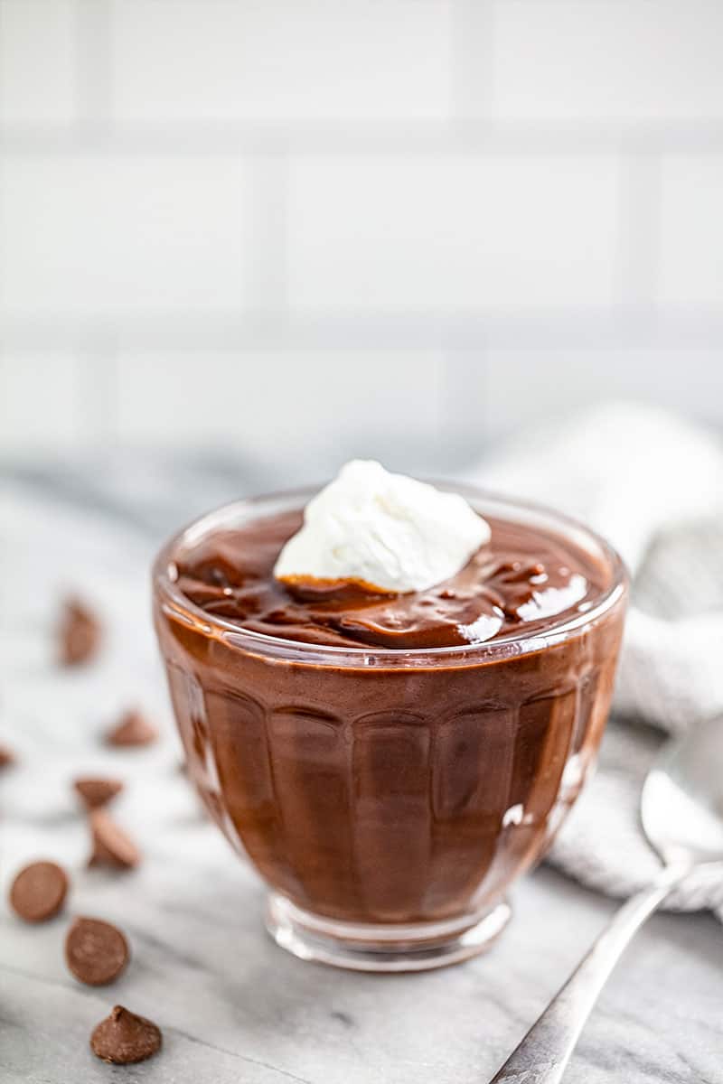 Chocolate Pudding in a glass dish topped with whipped cream.