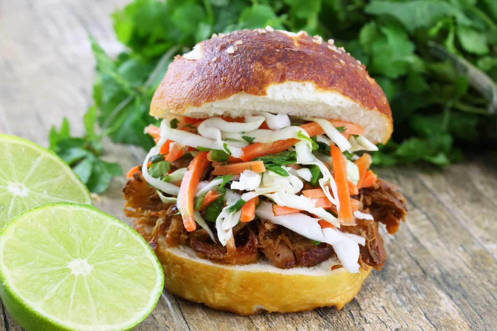 Pulled pork sandwich on a white plate topped with a Thai Slaw on a white plate