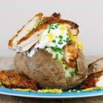 Fried chicken stuffed into a baked potato on a blue plate.