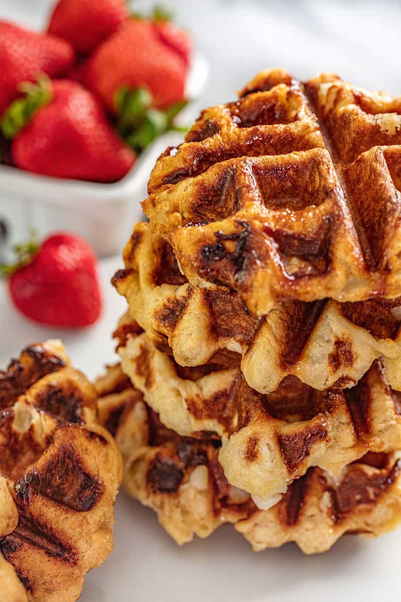 A stack of Liege Waffles with fresh strawberries in the background