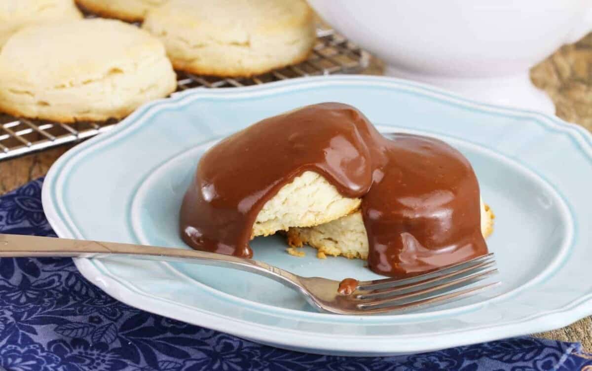 A sweet biscuit cut in half with chocolate gravy drizzled on top