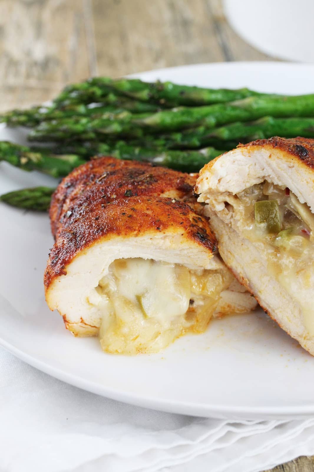Cajun-spiced chicken breasts stuffed with bell peppers, mushrooms, and onions and zesty pepperjack cheese on a plate with asparagus