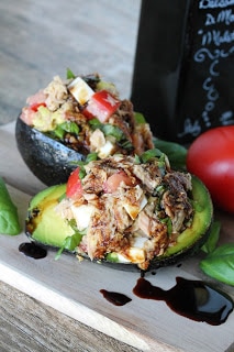 Two pieces of Caprese Stuffed Avocado drizzled with balsamic vinegar