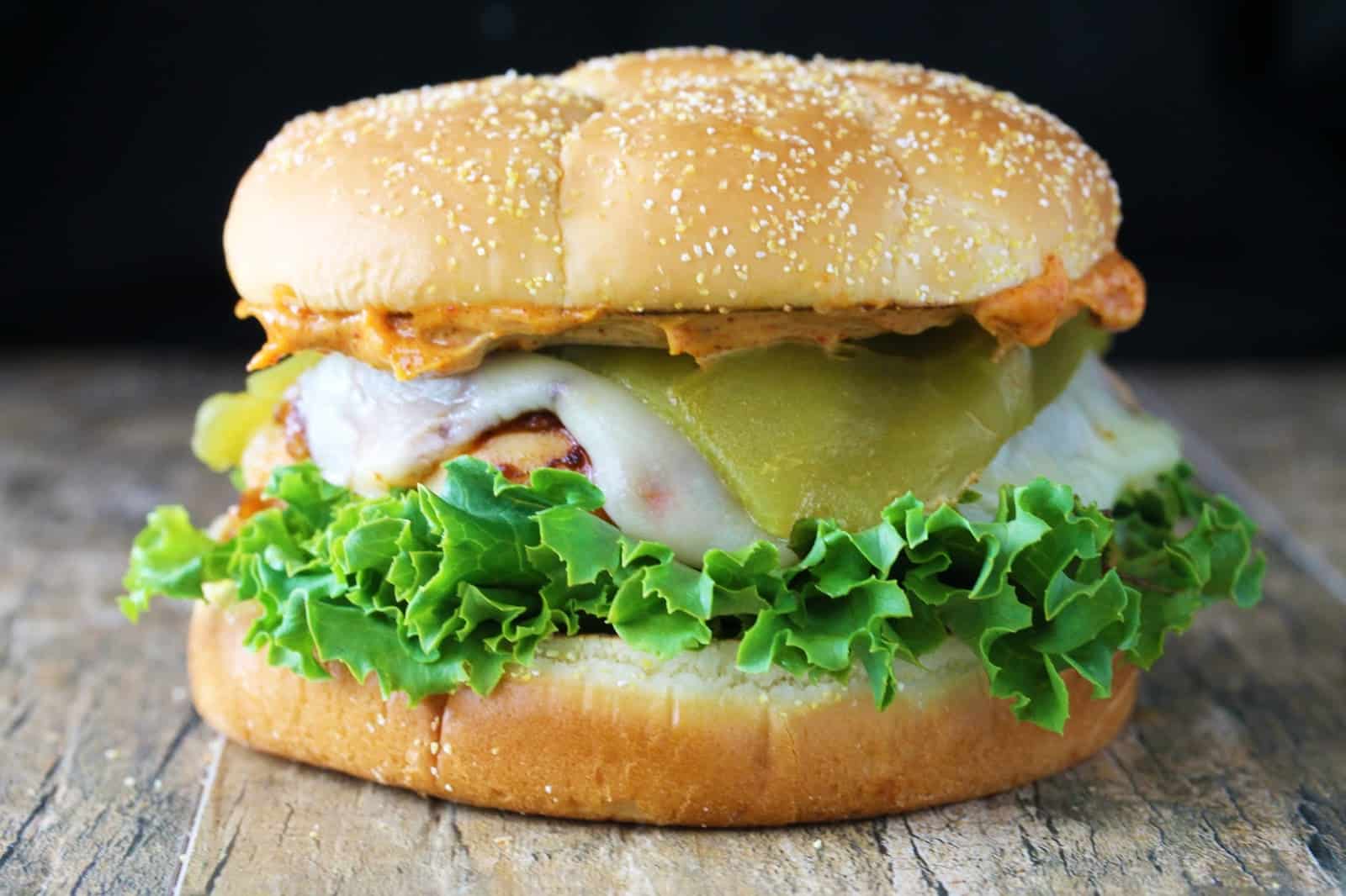 Close up view of a santa fe chicken sandwich on a wooden table with a black background