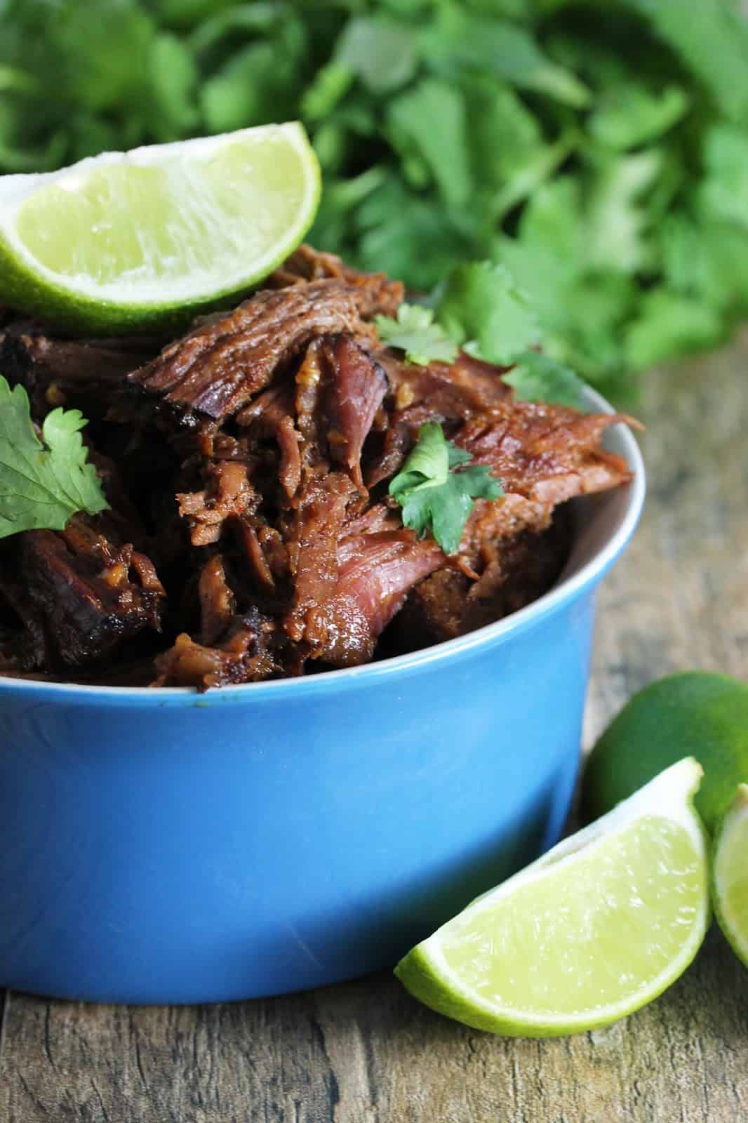 Easy Slow Cooker Chili-Lime Mexican Shredded Beef in a Crockpot, garnished with cilantro and fresh lime wedges