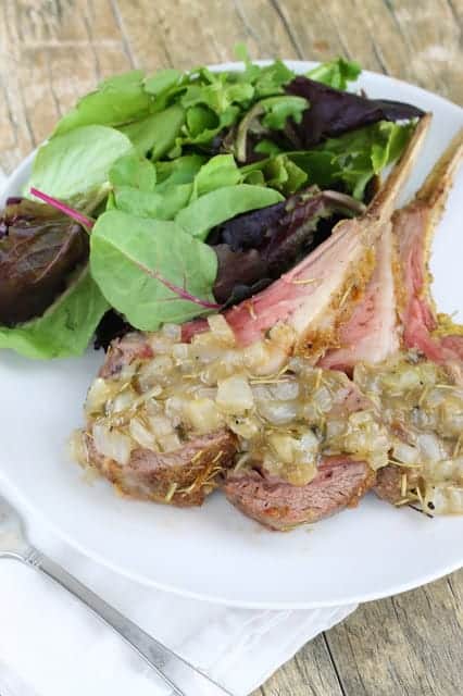 Mustard Crusted Rack of Lamb with Herb Sauce paired with a salad on a white plate.