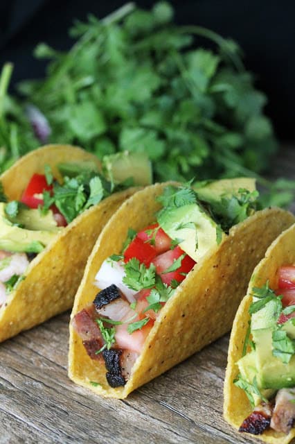 Ancho chili crispy pork belly tacos with cilantro and avocado 