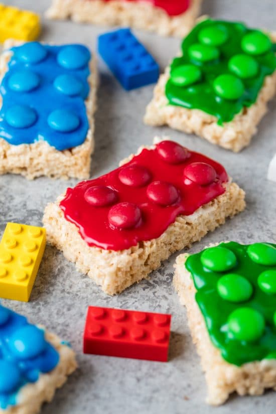 Lego Rice Krispie Treats in the shape of toy legos frosted with red, blue, and green icing and topped with coordinating colored M&M candies