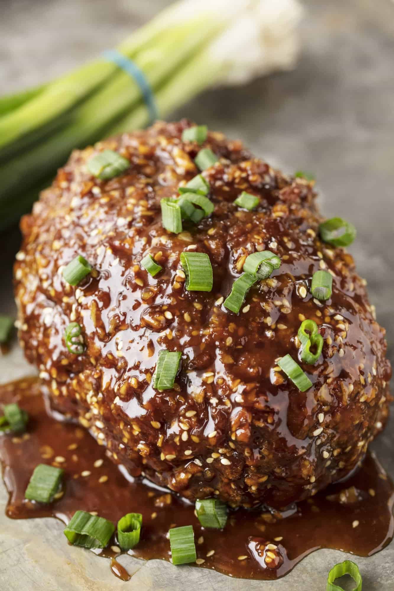 Korean Meatloaf topped with a glaze and green onions.