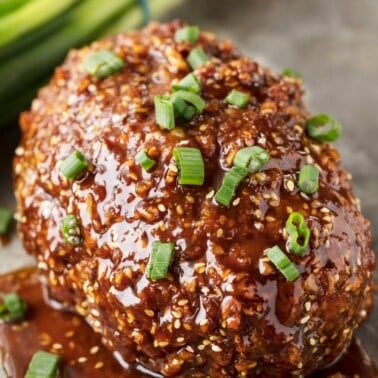 Korean Meatloaf topped with a glaze and green onions.