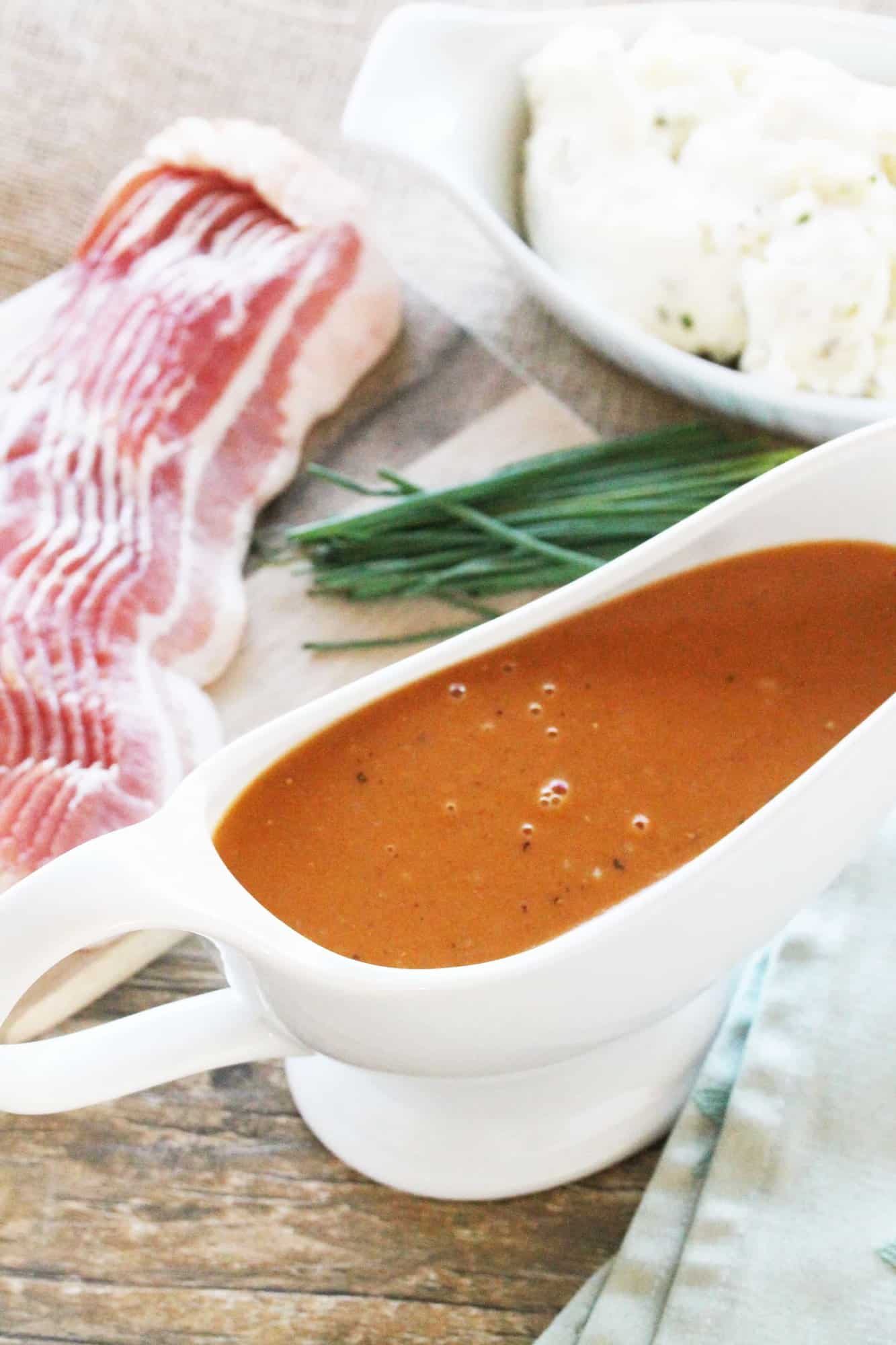 Bacon gravy in a gravy boat by chives and bacon.