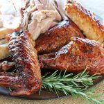 Roasted turkey on a platter with light meat, dark meat and wings and drumsticks with deliciously crispy skin. All garnished with a sprig of rosemary.