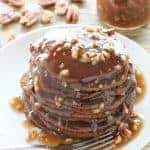 A stack of Gingerbread Pancakes on a plate, smothered with Butter Pecan Syrup and chopped pecans