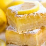 Two lemon bars stacked on top of each other and topped with a lemon slice