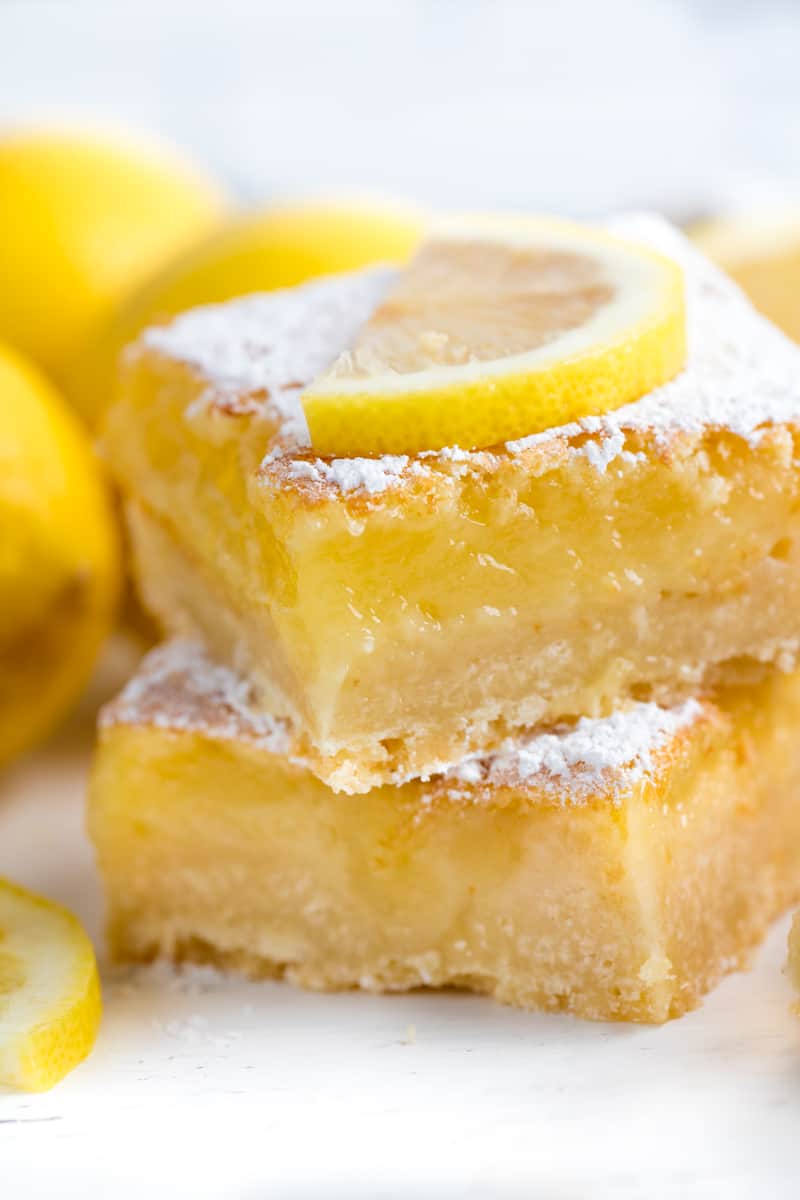 Two lemon bars stacked on top of each other and topped with a lemon slice